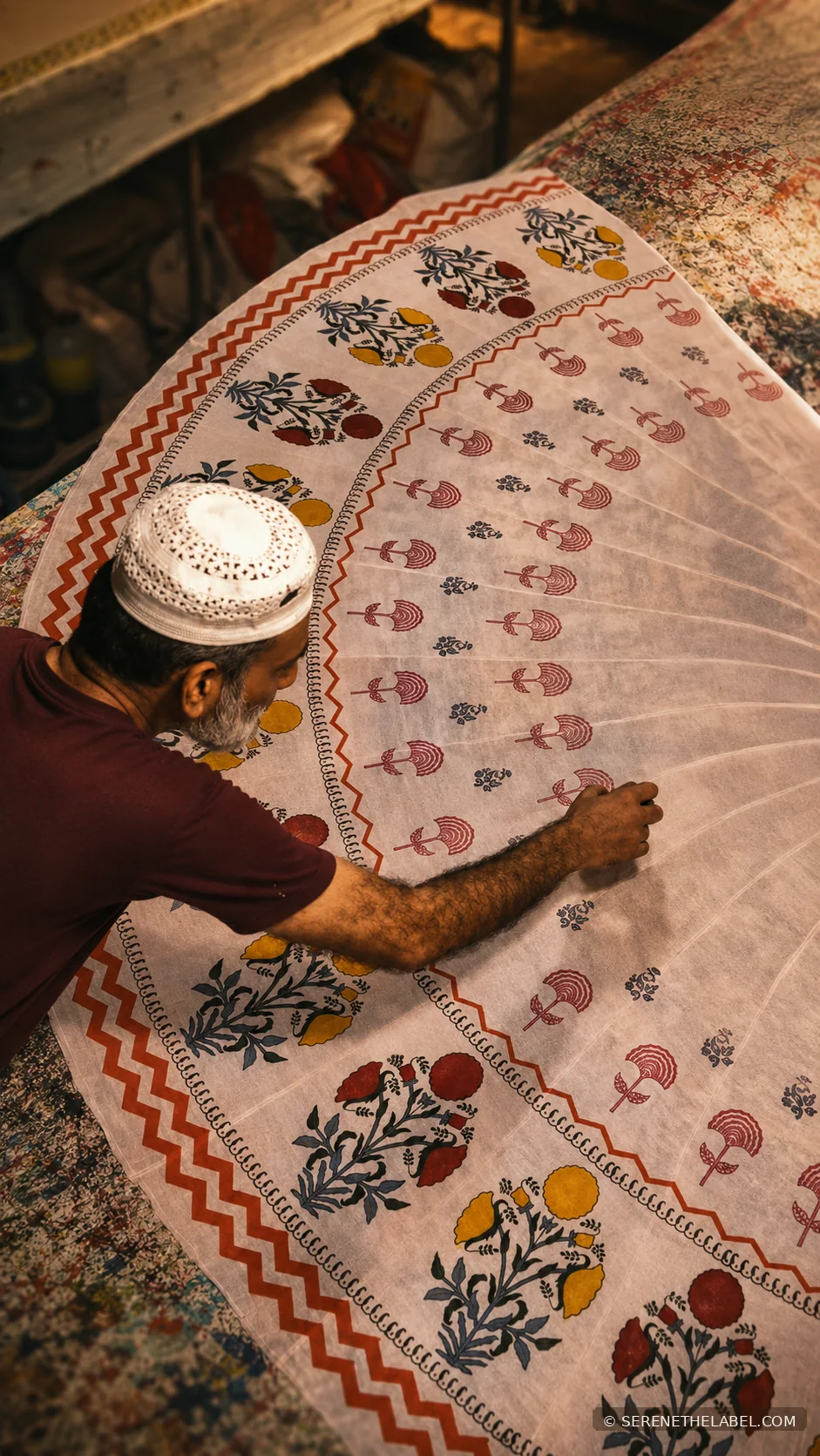 Craftsperson arranging a large hand-printed fabric panel on a work table